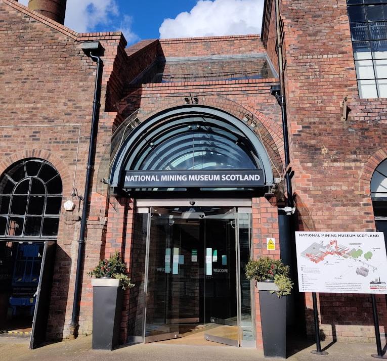 Front of the National Mining Museum Scotland, a red stone building with an arched doorway.